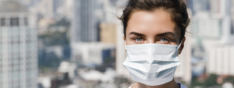 Wanita sedang menggunakan masker saat keluar rumah