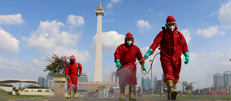 pekerja yang sedang memberikan disinfektan pada jalan